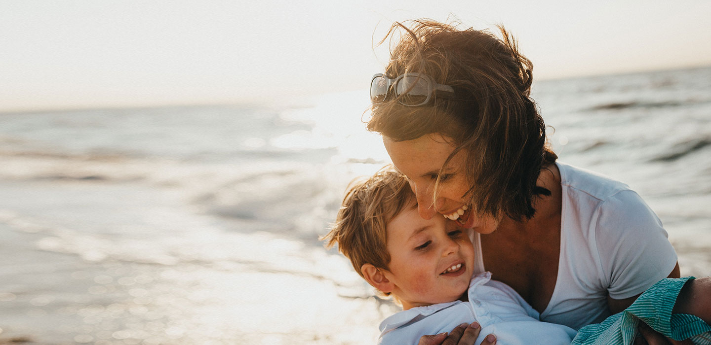 A parent holding a laughing child close at the water’s edge